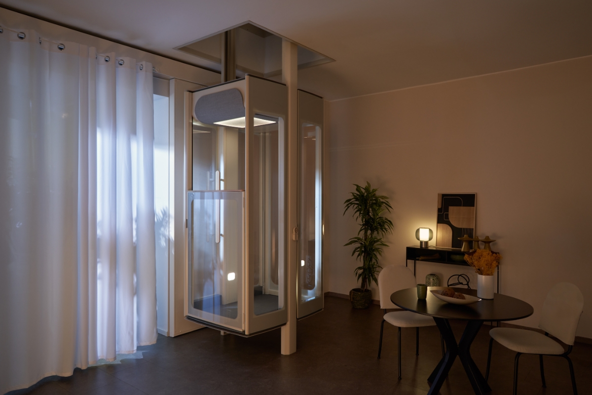 Domáci výťah Stannah Uplifts v noci s vnútorným osvetlením, zaparkovaný medzi poschodiami v modernom obytnom priestore.